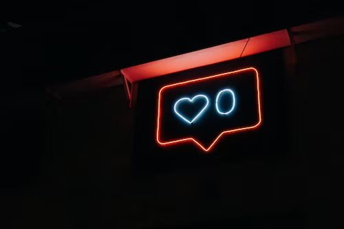 Neon sign displaying a blue heart and zero which signify social media engagement. 