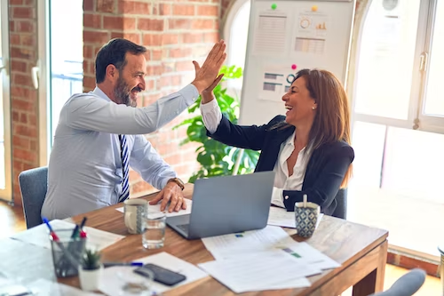 A man and a woman high-fiving each other for their Instagram business growth.