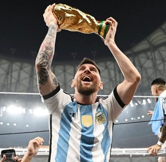 Foto di Leo Messi che regge il trofeo della Coppa del Mondo FIFA.