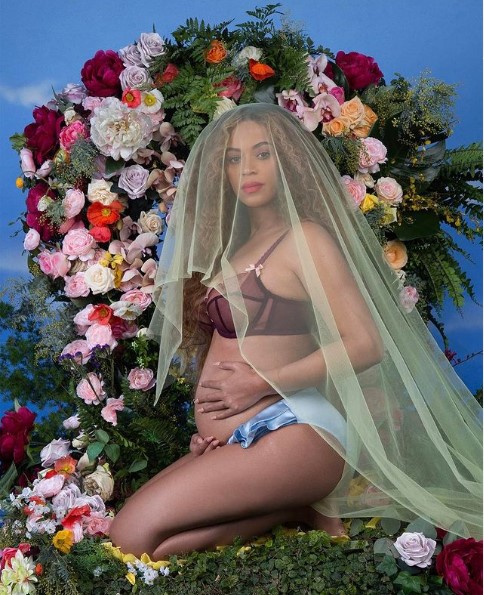 Pregnant woman kneeling in front of flowers
