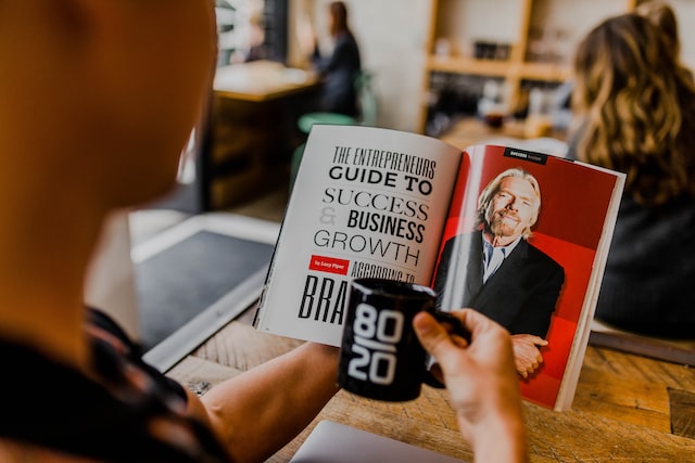 Person reading a magazine article about how to succeed in business.