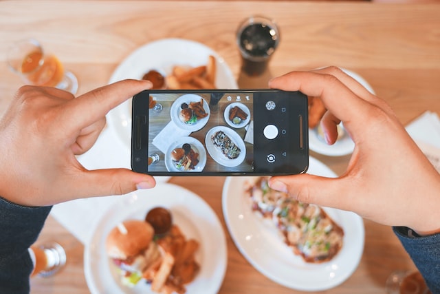 Person, die mit einem Smartphone ein Foto von einem Lebensmittel macht