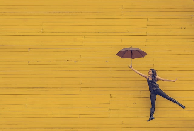 Eine Frau, die mit einem Regenschirm in der Hand springt, symbolisiert einen Follower-Boost auf Instagram.