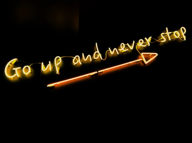 Neonschild mit der Aufschrift "Go up and never stop" und einem Pfeil, der nach oben zeigt, um das Wachstum von Instagram darzustellen. 