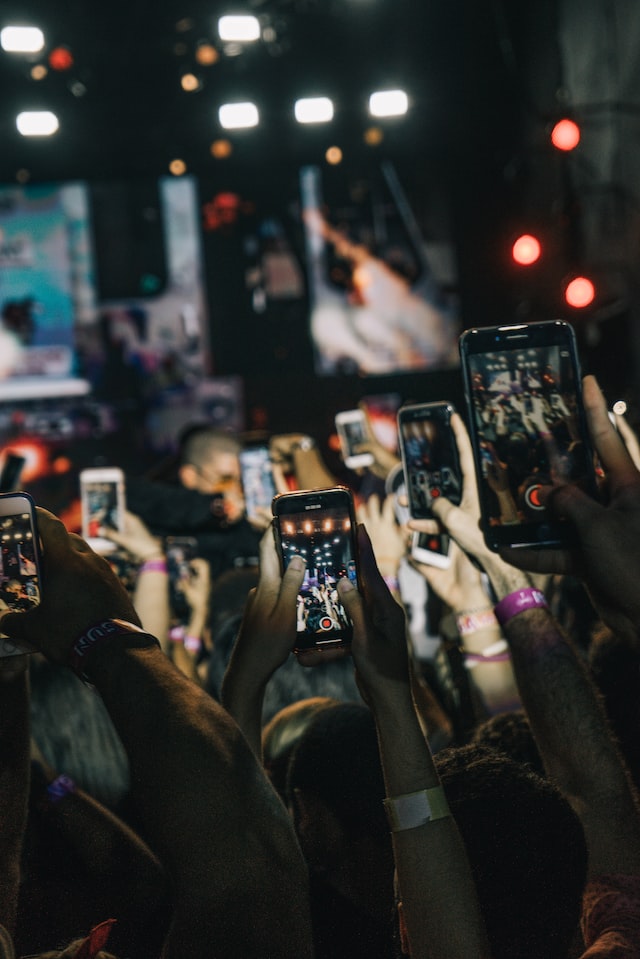 Persone che tengono i loro telefoni in alto e registrano un video