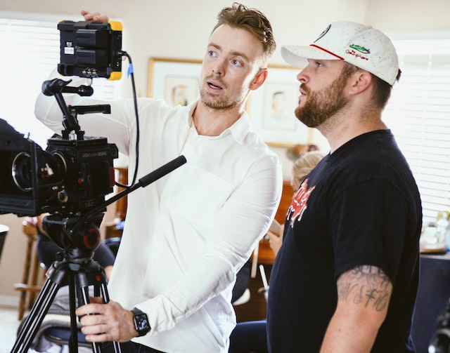 Photo of a group of men on set and discussing a scene to demonstrate what goes on behind the scenes for an Instagram post. 