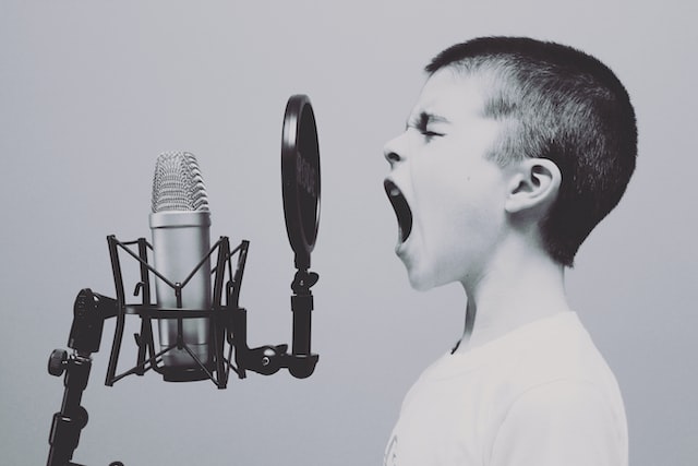 Ein Junge, der in ein Mikrofon schreit, um aktive Diskussionen über eine Marke auf Instagram und anderen Social-Media-Plattformen darzustellen. 