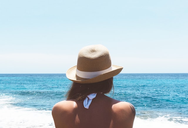 Mädchen mit Sommerhut am Strand.