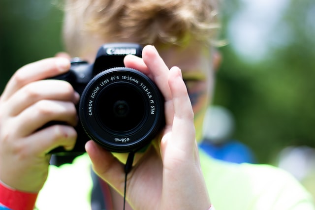 Hombre sosteniendo una cámara DSLR y creando un vídeo tutorial para ganar dinero en Instagram. 