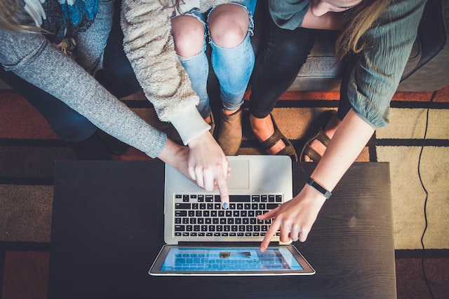 Um grupo de mulheres em frente a um laptop criando conteúdo para um Instagram colaboração. 