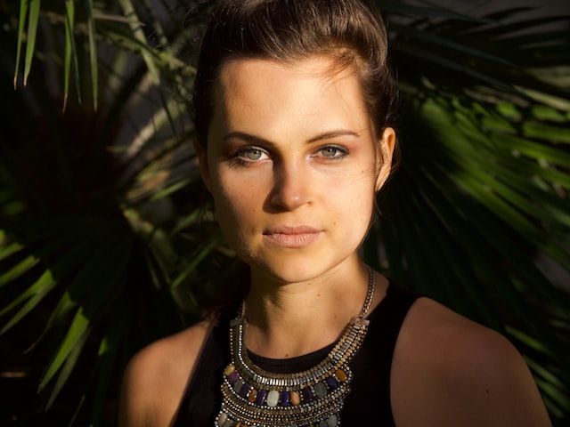 Headshot of a woman with leaves in the background.