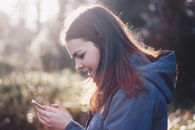 O femeie care se uită pe telefon la un videoclip care arată cum să eticheteze produsele în postările din feed pentru Instagram Shop.