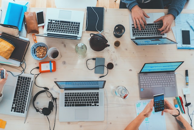 People around a table using laptops to find potential new followers on Instagram. 