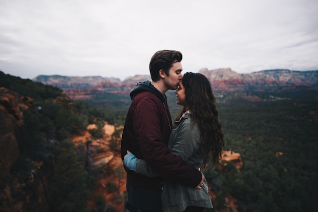 Casal abraçado no cimo de uma montanha.