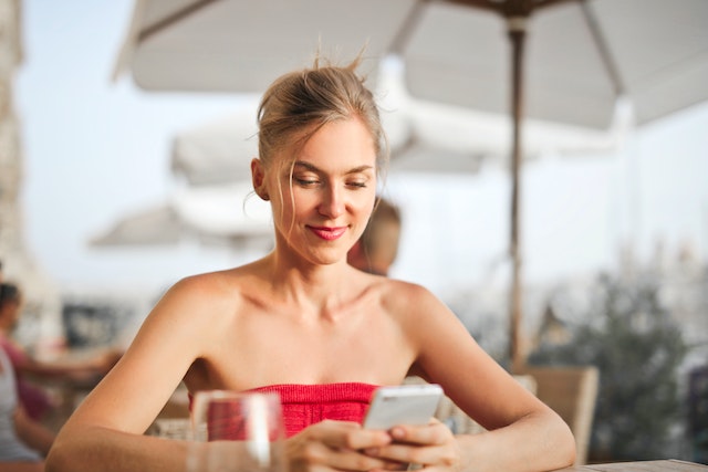 Vrouw kijkt naar haar telefoon en leert hoe ze de betrokkenheid van haar volgers kan verbeteren.