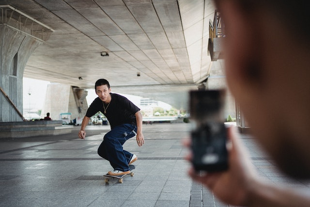 Instagram でリールの作り方を学ぶため、スマートフォンでスケートボーダーの写真を撮る人。