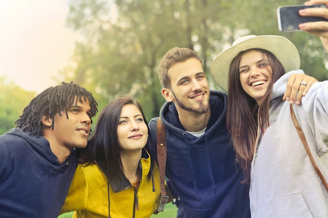 Groep mensen die een selfie nemen in de buitenlucht om te gebruiken bij het leren hoe je een verhaal opnieuw kunt posten op Instagram.