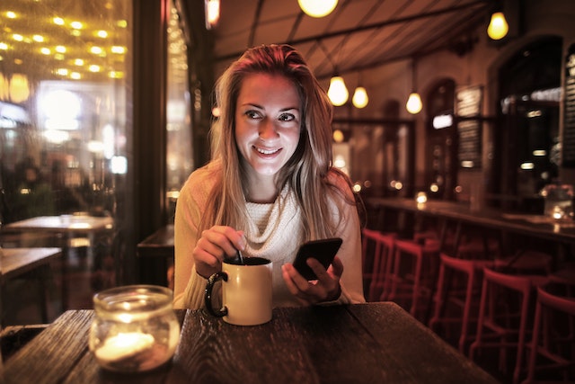 Vrouwen met een smartphone leren hoe ze meerdere foto's kunnen toevoegen aan een Instagram-verhaal.