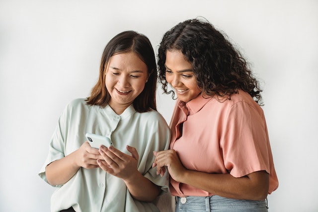 Dos personas mirando sus teléfonos para que una le enseñe a la otra a añadir varias fotos a las historias de Instagram.