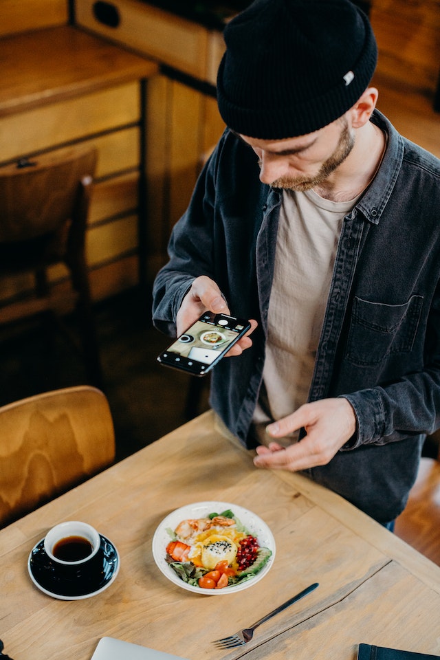 Persoană care face fotografii de produse alimentare pentru a partaja în care acestea să învețe cum să devină un influencer alimentare.