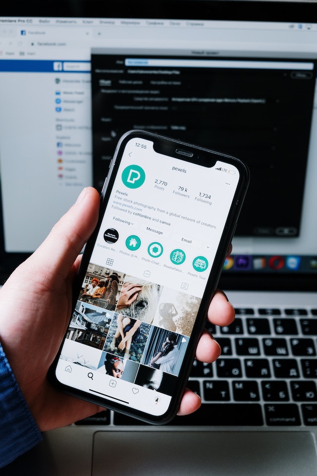 Hands holding black smartphone displaying Instagram profile.