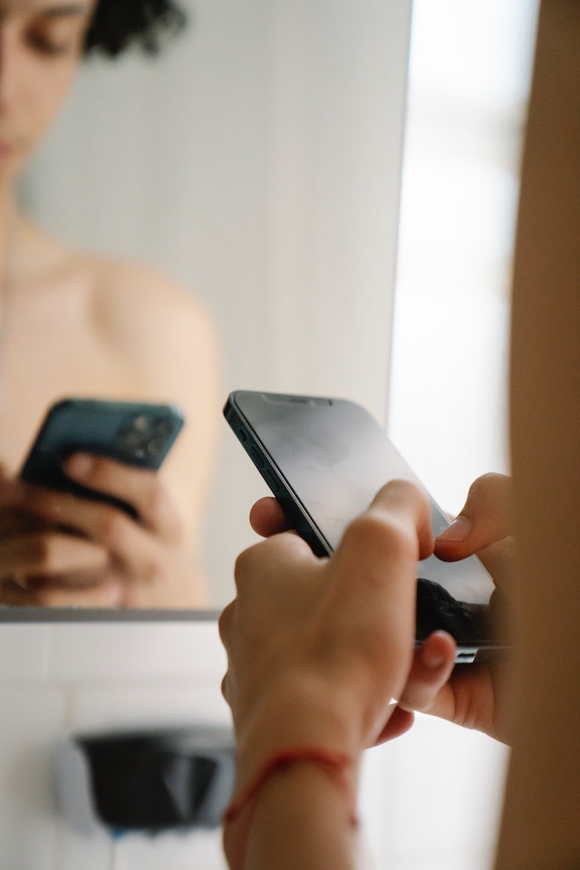 Gros plan des mains d'une femme tapant sur un smartphone pour ajouter un lien à une story Instagram.