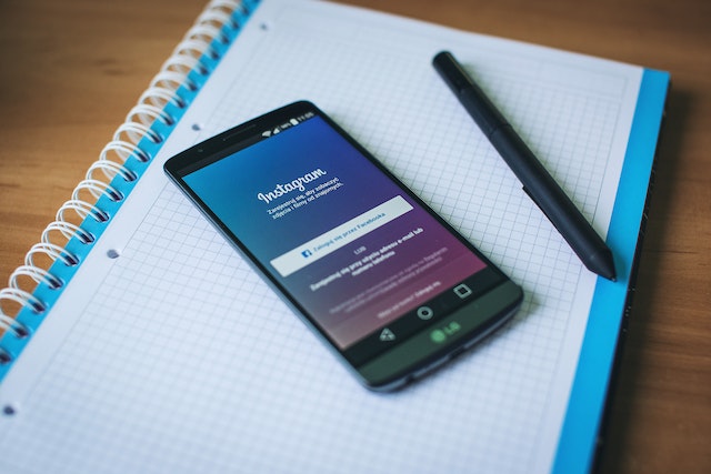 pexels-freestocksorg-35177-1-1 | Path Social メモ帳の上に置かれたスマートフォンで、Instagram のログイン画面を開く。