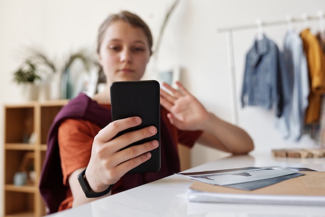 Junge Frau mit Smartphone in der Hand, die herausfinden will, wie man mehrere Fotos zu Instagram hinzufügen kann.