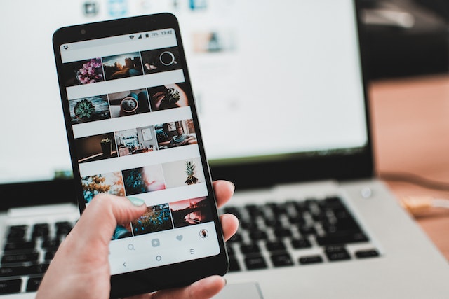 Smartphone aperto all'app Instagram davanti a un computer.