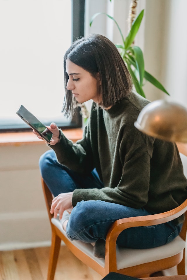 Person looking at smartphone, watching content from her favorite macro influencers on Instagram.