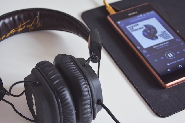 Photo of a headphones beside a phone while playing music.