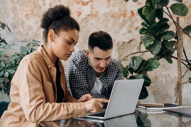 Due persone sedute davanti a un computer portatile che discutono della loro strategia di crescita su Instagram.