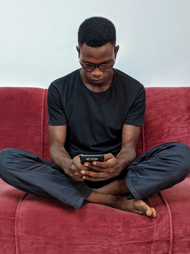 pexels-oladimeji-ajegbile-2364447-1 | Path Social um homem sentado num sofá a olhar para um telemóvel