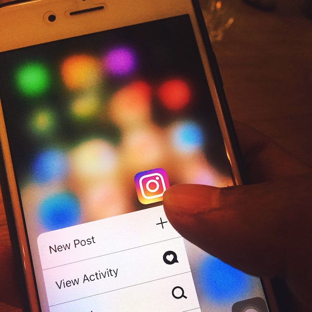 Persona que utiliza un smartphone para publicar en Instagram con la ayuda de una empresa de gestión del crecimiento social.