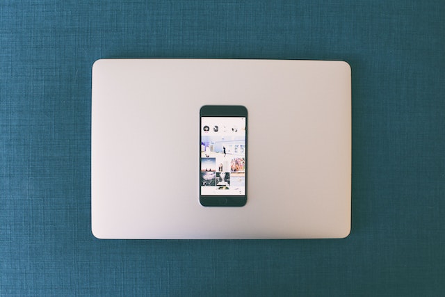 Smartphone laying on top of a laptop computer.