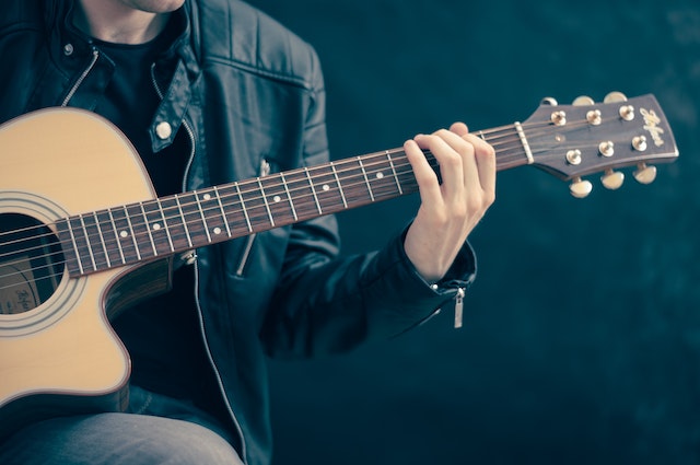 Eine Gitarre spielende Person, die den Beitrag Instagram mit Musik unterlegt.