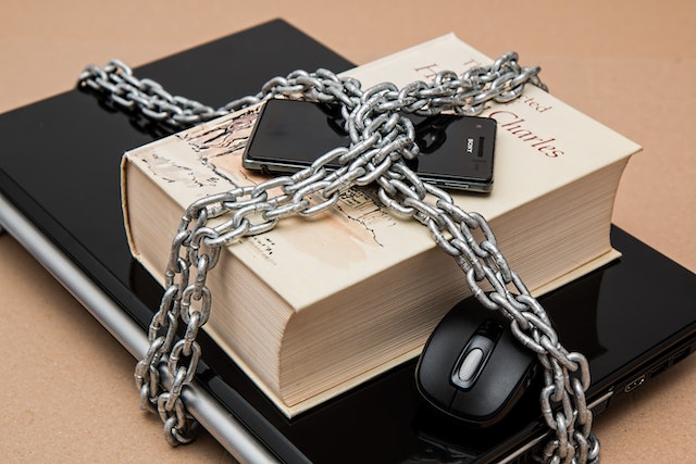 Black smartphone chained on top of large white book.