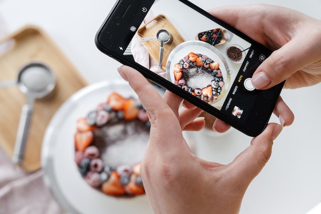 Frau, die ein Foto mit einem Smartphone macht, in der Hoffnung, eine Instagram Influencerin zu werden.