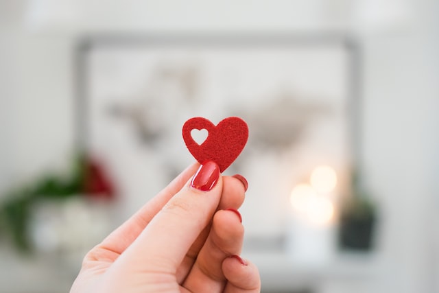 Woman's hand holding a small red heart.
