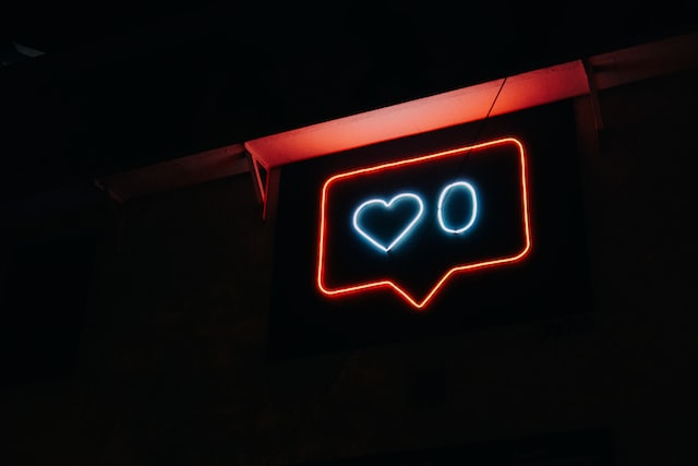 Neon sign displaying a blue heart and zero which signify social media engagement. 