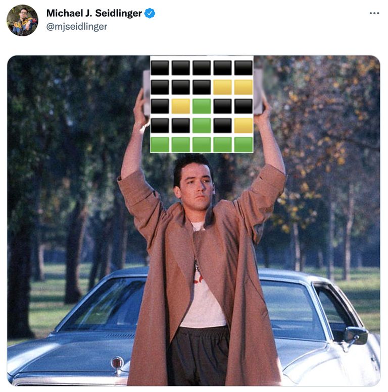 Actor lifting a sign with Wordle's black, green, and yellow blocks.