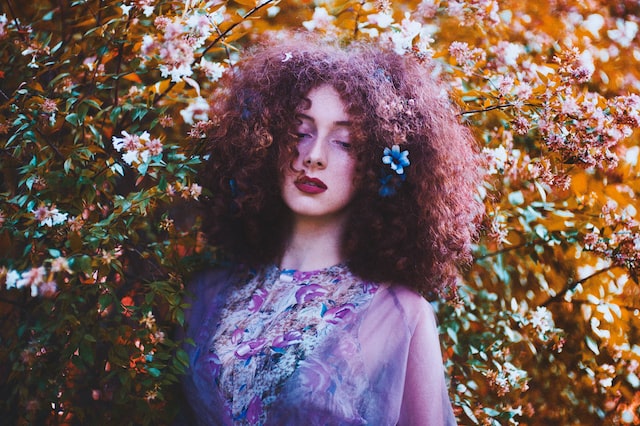 Professional and artistic shot of a woman in front of a floral bush.