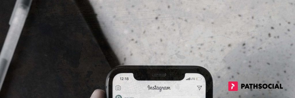 Path Social gráfico sobreposto a um telemóvel com o logótipo Instagram , com uma caneta, um bloco de notas e uma mesa em segundo plano.