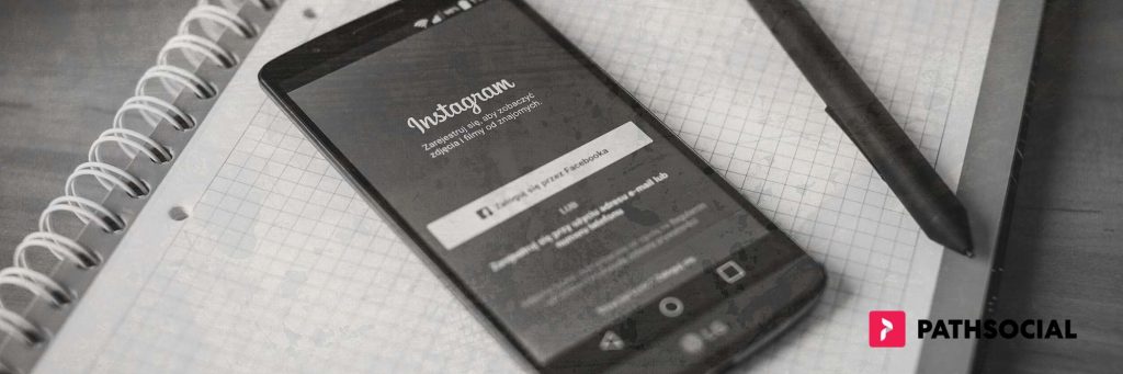 Path Social grafica che sovrappone un telefono cellulare che visualizza la schermata di login di Instagram sopra un quaderno e accanto a una penna.