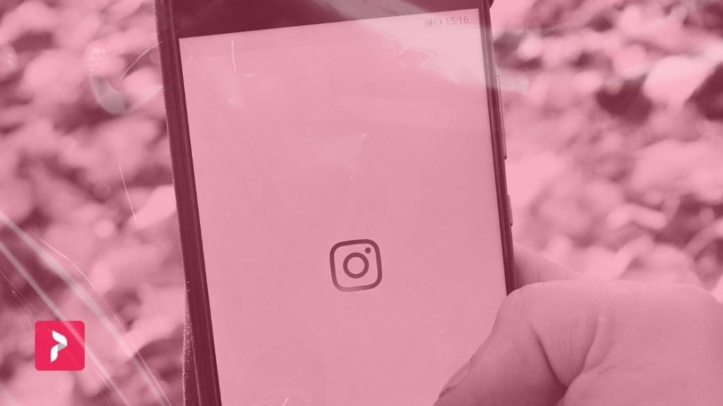 Path Social Logótipo e filtro vermelho sobre uma mão que segura um telemóvel com o logótipo Instagram .