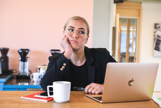 Uma mulher de negócios em frente ao seu computador portátil pensa nos melhores fornecedores de pacotes de seguidores.