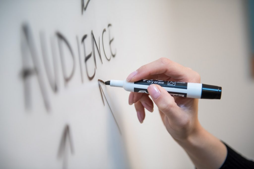 Persoon die het woord "publiek" op een whiteboard schrijft. 