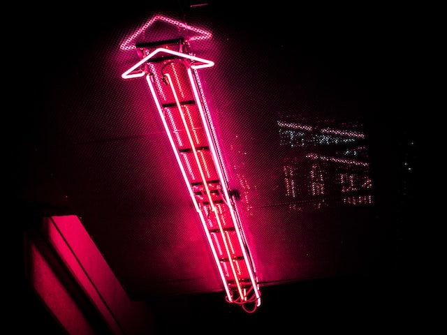 Red neon arrow light pointing up to indicate growth through Instagram like apps. 