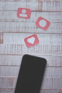 Picture of phone with symbols of hearts comments and likes inside speech bubbles