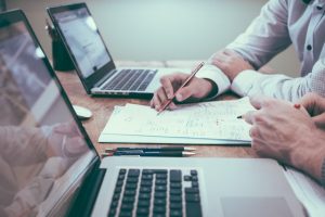 Doi oameni de afaceri în fața laptopurilor lor discută despre legalitatea pachetelor de followeri